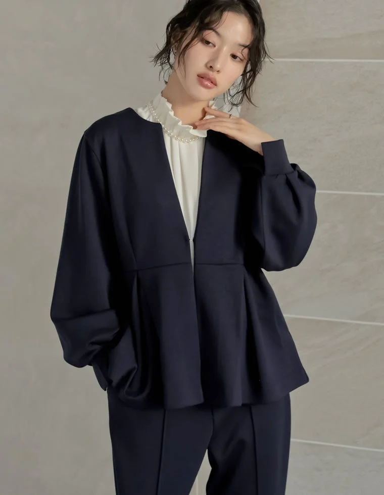 ネイビーのペプラムジャケットとパンツのセットアップ、白いフリルブラウスとパールネックレス