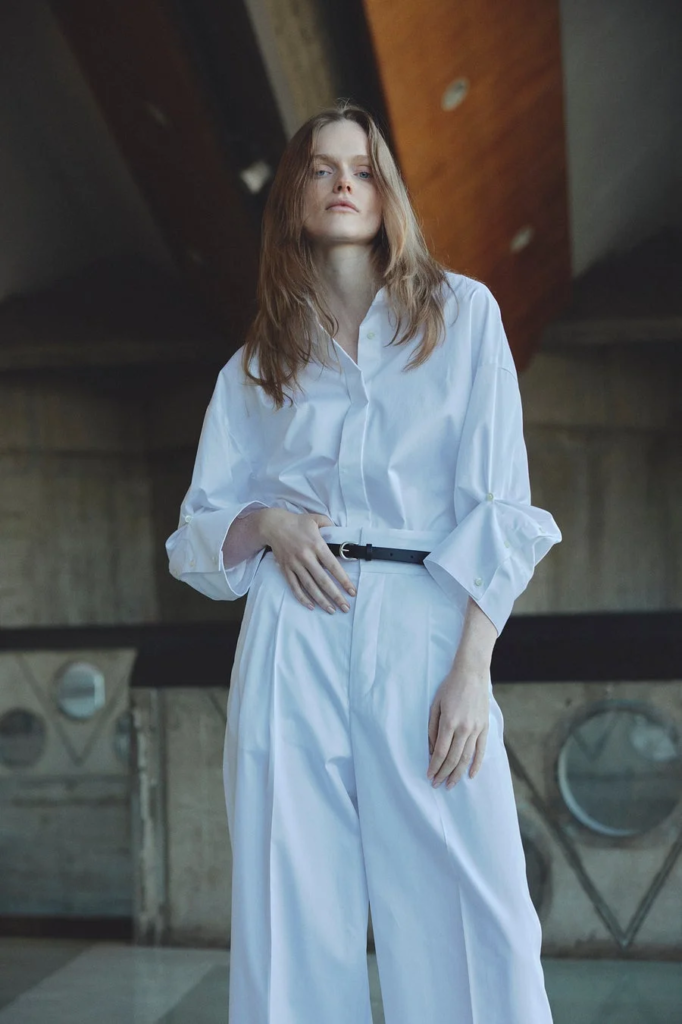 白いオーバーサイズのシャツとワイドパンツを着用した女性