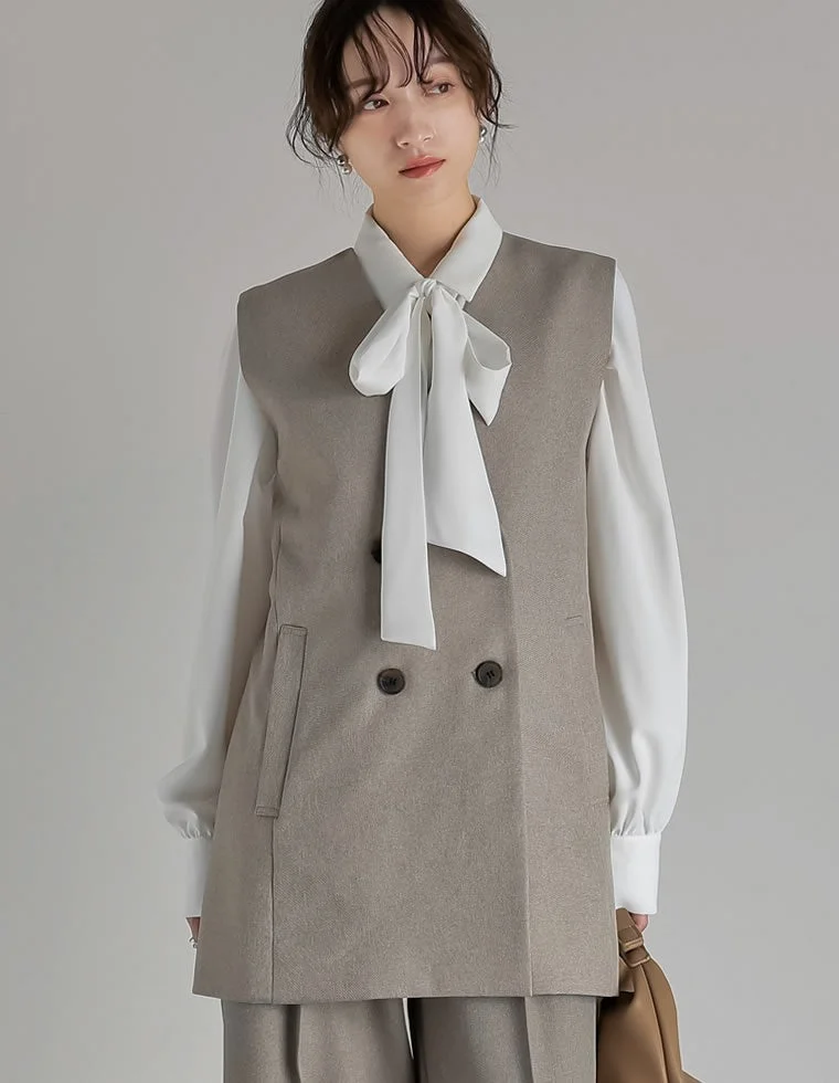 白いボウタイブラウスにグレージュのダブルボタンベストとパンツのセットアップ