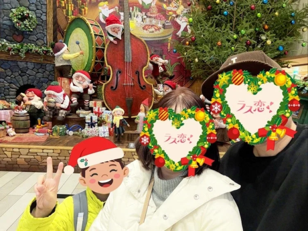 クリスマスをテーマにした華やかなディスプレイの前でポーズをとる家族の写真