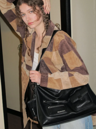 パッチワークジャケットと大きな黒いバッグを持つ女性