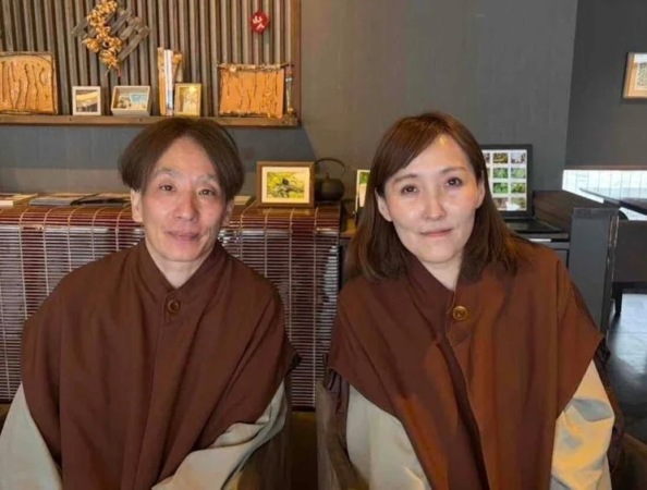 和風の室内で、茶色い上着をまとった男女が並んで座り、穏やかな笑顔を向けている様子