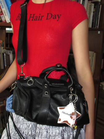 赤いTシャツの人物と黒いショルダーバッグ