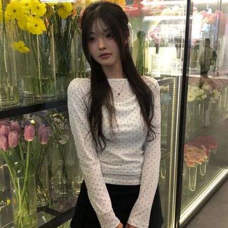 ポルカドット柄の白いトップスと黒いスカートを着用した女性