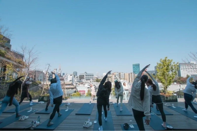 屋上でピラティスをする参加者たち