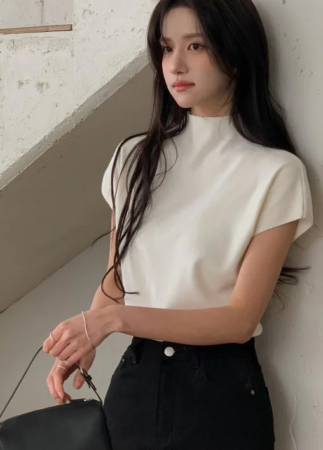 白いモックネックのトップスと黒いパンツを着用した女性