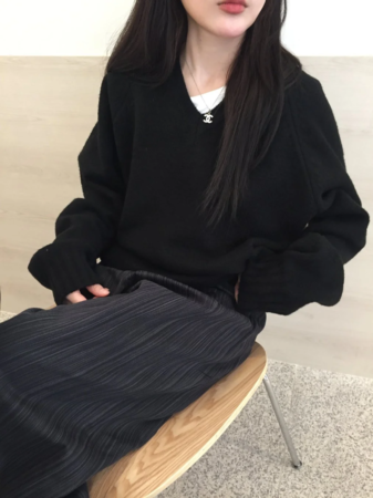 黒いVネックセーターとストライプのワイドパンツを着用した女性