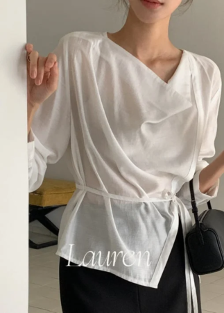 白いドレープブラウスと黒いボトムスを着用した女性