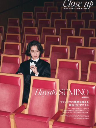 劇場のような赤い座席に座るタキシード姿のピアニスト角野隼斗