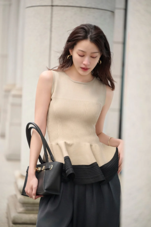 ベージュのノースリーブペプラムトップスと黒のワイドパンツ