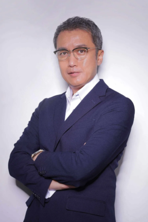 紺色のスーツと眼鏡を着用した中年のアジア人男性が腕を組み、カメラを見つめているポートレート