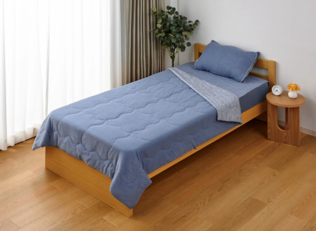 青い寝具が整えられたシンプルなシングルベッドが置かれた寝室の様子