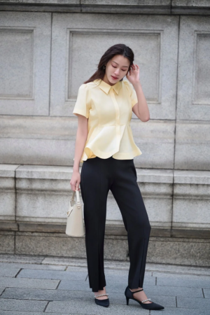 黄色いペプラムブラウスと黒いパンツ