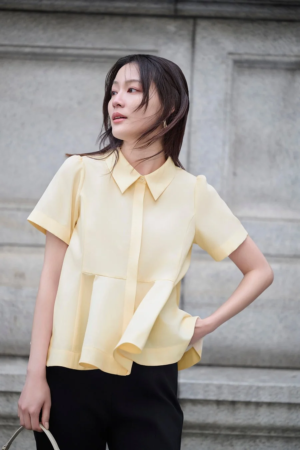 薄黄色の半袖ブラウスと黒いパンツ