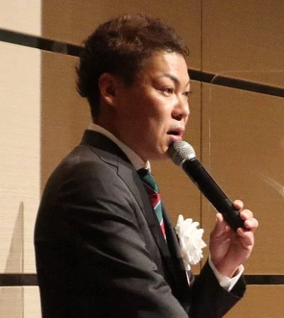 マイクを持ってスピーチする男性