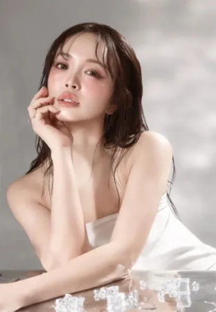 濡れた髪と柔らかなメイクの女性が白いチューブトップを着用し、氷が散らばる中で優雅にポーズをとっています。クールでフレッシュな雰囲気が漂うポートレートです。
