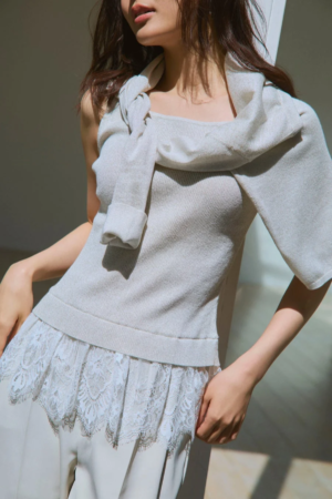 淡い色のニットアンサンブルを着用した女性