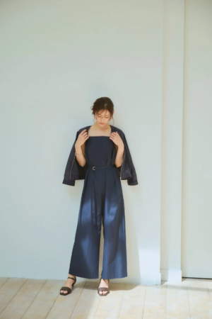 ネイビーのジャンプスーツにジャケットを羽織った女性