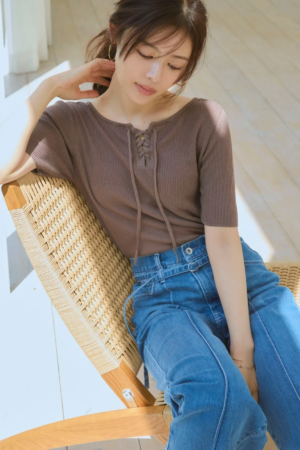 ブラウンのトップスとデニムを着用した女性