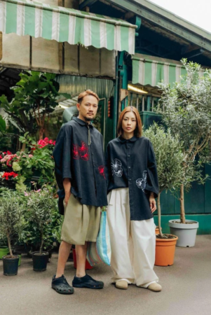 植物に囲まれた屋外に立つカップル（Aïdama）