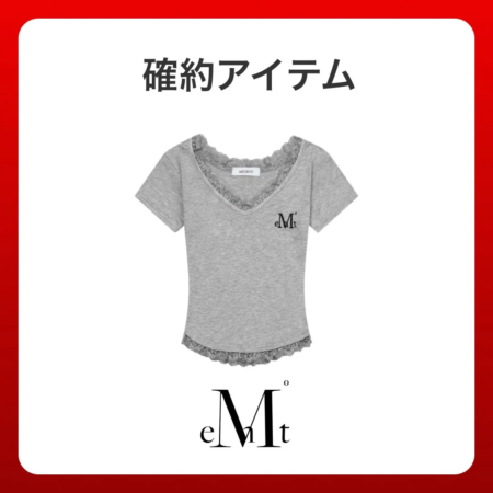 グレーのVネック半袖Tシャツで、胸元に「eMt」のロゴがあり、襟ぐりと裾にレースがあしらわれています。