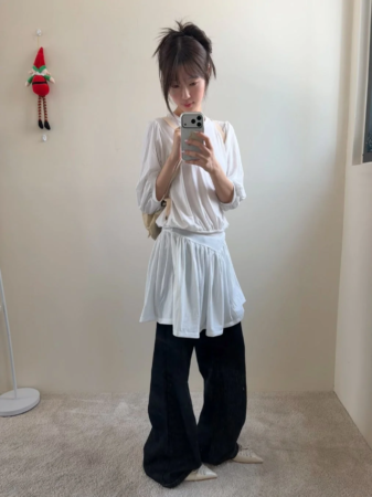 白いトップスと黒いワイドパンツを着用した女性の全身ミラーセルフィー