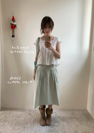 白いフリルブラウスとミントグリーンのプリーツスカートを着用した女性のファッションスナップ