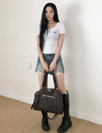 ダークブラウンのバッグを持つ女性の立ち姿