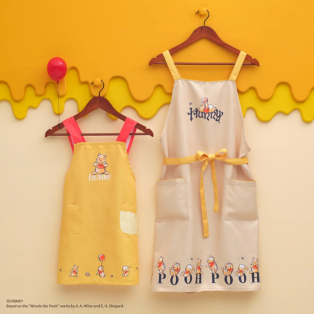 くまのプーさんのイラストと「HUNNY」「POOH POOH」の文字がデザインされた大小2種類のエプロン