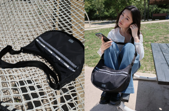公園でイヤホンをつけスマートフォンを操作する女性と黒いショルダーバッグ