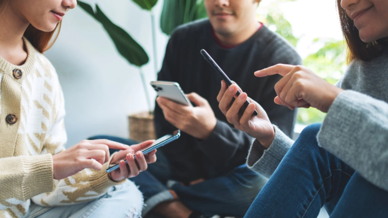 3人の人物がそれぞれスマートフォンを操作している様子