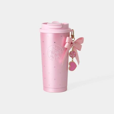 ピンク色のスターバックスのタンブラーで、リボンとロリポップ、ハートのチャームが付いています。
