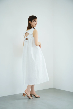 白いバックリボンデザインのノースリーブワンピースを着た女性