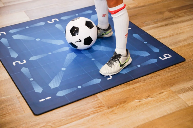 サッカーボールとトレーニングマットの上で、サッカーシューズを履いた足元