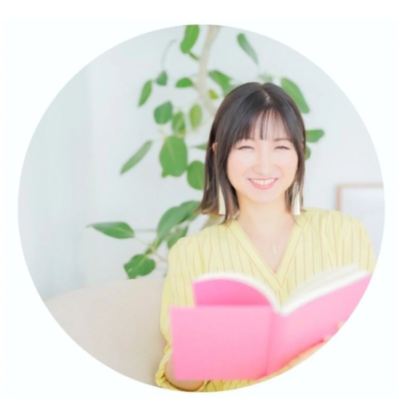 明るい笑顔の女性がピンク色の本を持って座っているポートレート