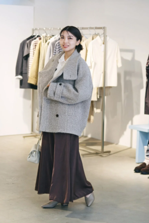 グレーのオーバーサイズコートとブラウンのワイドパンツを着用した女性