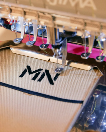 刺繍機が布に「MN」の文字を刺繍している様子