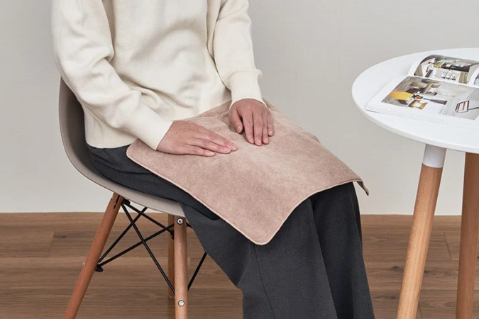 膝の上にクッションを置いてくつろぐ様子